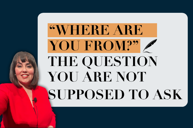 A woman with shoulder-length brown hair wearing a red blazer and a clip-on microphone, smiling at the camera in a podcast-style selfie shot. She's positioned on the left against a dark navy background. To the right, a light gray rounded rectangle contains bold black text reading "WHERE ARE YOU FROM?" (highlighted in orange) and "THE QUESTION YOU ARE NOT SUPPOSED TO ASK," with a small quill pen icon beside the highlighted text.